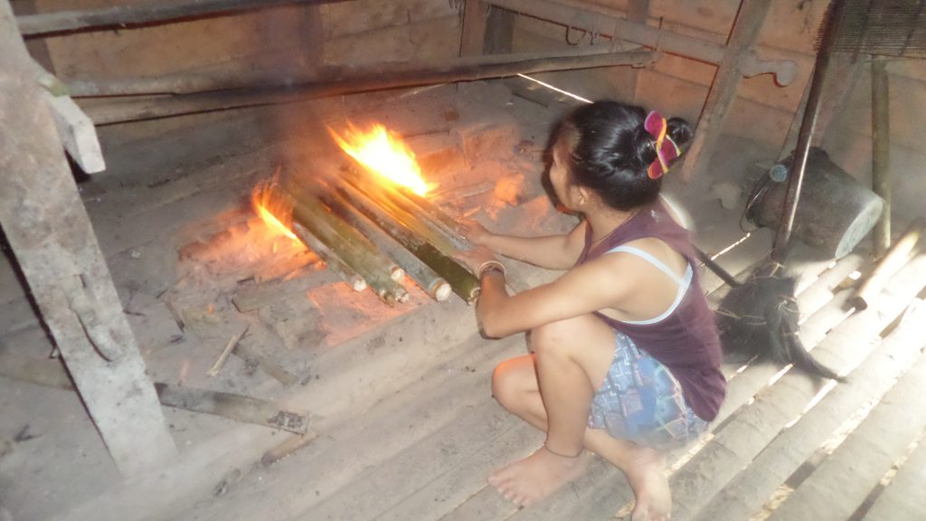 Preparing sago over fire in bamboo